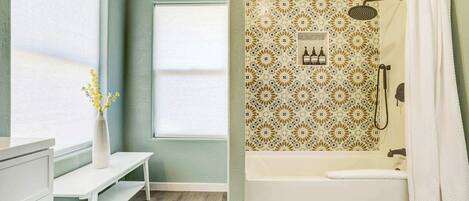 A bathroom with a shower, a window, and a white sink.