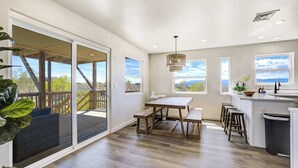 A spacious kitchen with a dining area, large windows, and a view of the outdoors. - 3BR Retreat with Hot Tub, Deck, Fire Pit,Sleeps 10 (Pueblo)