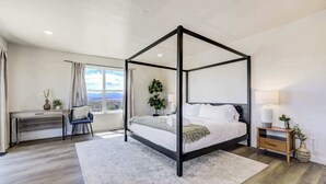 A modern bedroom with a four-poster bed, a desk, and a view of the outdoors. - 3BR Retreat with Hot Tub, Deck, Fire Pit,Sleeps 10 (Pueblo)
