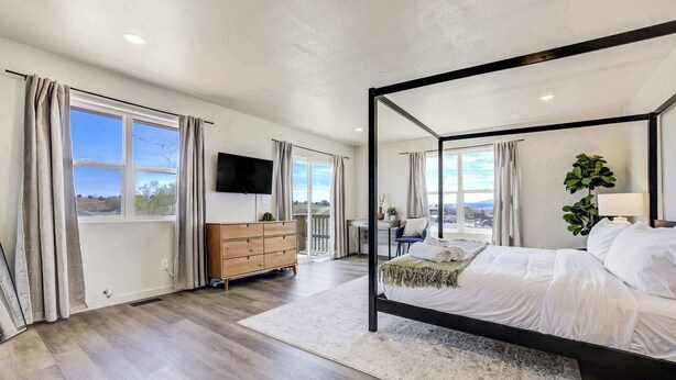 A bedroom with a four-poster bed, a desk with a chair, a TV, and a view of the outdoors. - 3BR Retreat with Hot Tub, Deck, Fire Pit,Sleeps 10 (Pueblo)