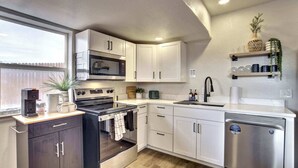 Una cocina moderna con armarios blancos, horno empotrado, lavavajillas y ventana que aporta luz natural.