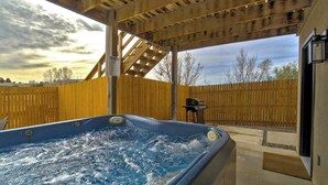Tinaco bajo una pérgola de madera con vista a una cerca de madera y árboles.