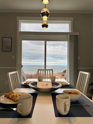 A dining area with a view of the ocean, a table with plates and cups, and a sign reading 'Welcome to Cabotopia.'