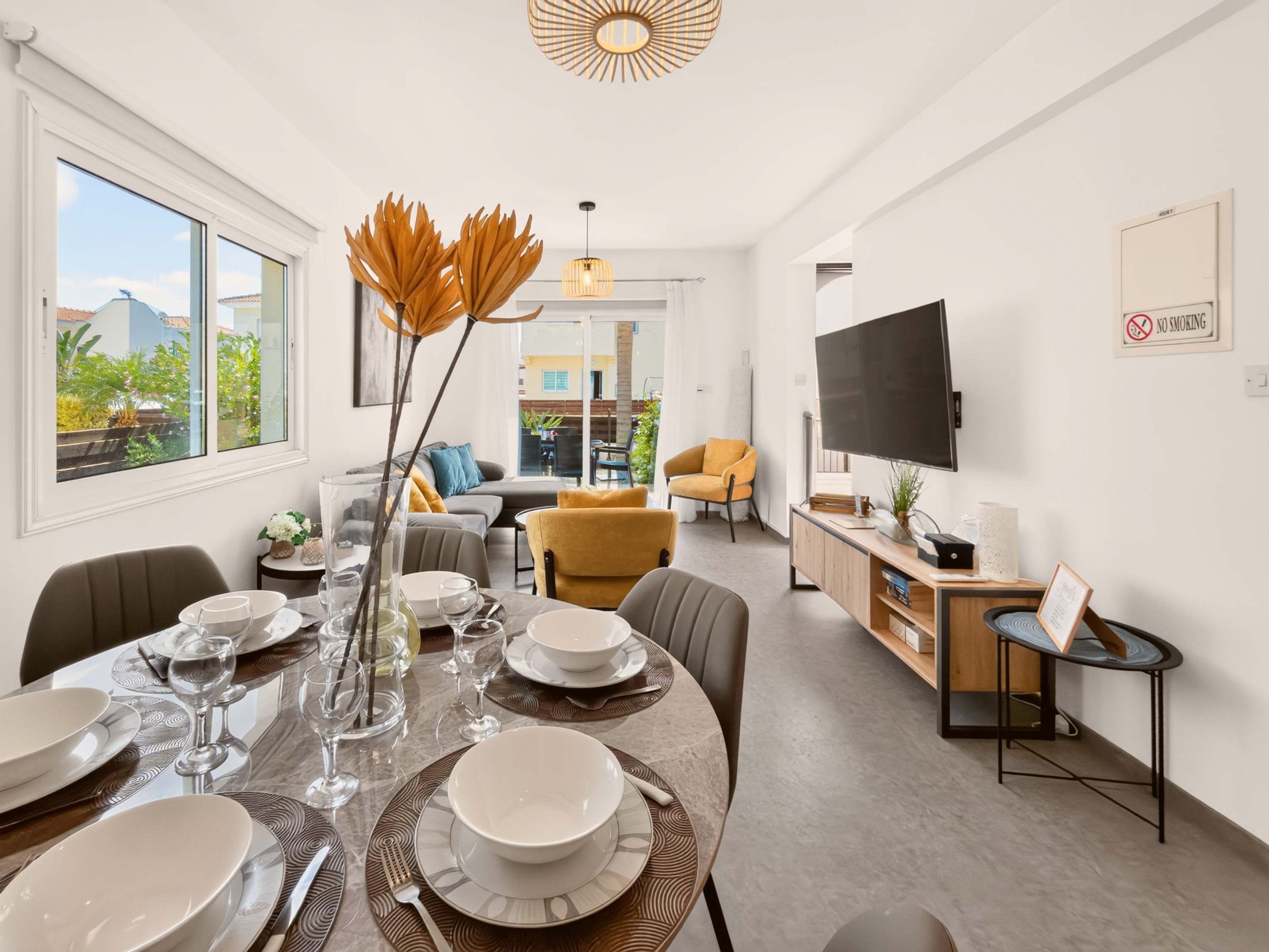Un salon moderne avec un coin repas, de grandes fenêtres et un téléviseur.