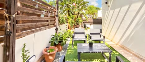 A patio area with a wooden pergola, outdoor seating, and potted plants.