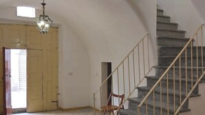 Eine Treppe mit Metallgeländer, ein Holzstuhl und eine Hängeleuchte.