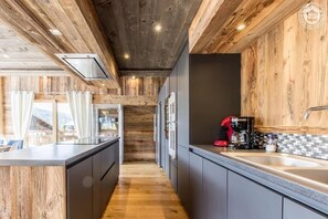 Eine moderne Küche mit Holzelementen, einer zentralen Kochinsel und Blick ins Freie.