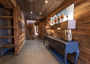 Ein Holzflur mit Treppe, einem blauen Konsolentisch und einem an der Wand befestigten Kunstwerk.