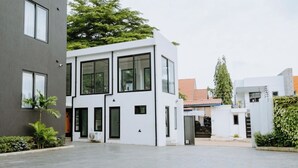 Un bâtiment moderne doté d’un toit plat, de grandes fenêtres et d’une cour dallée.