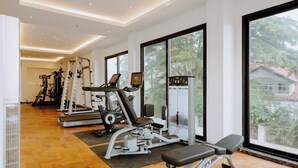 Une salle de sport moderne équipée de matériel d’exercice, dotée de grandes fenêtres et d’un plancher en bois.