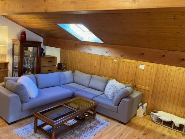 Een gezellige woonkamer met een modulaire bank, een bijzettafeltje en een dakraam.