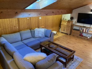 Een gezellige woonkamer met een hoekbank, een salontafel en een televisie.