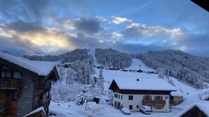 Een besneeuwde bergdorpsplaats met traditionele houten huizen, een skilift en een heldere lucht.