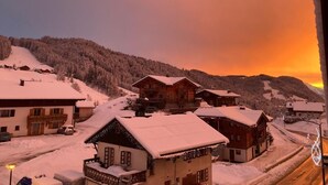 A snow-covered village with wooden houses and a sunset in the background. - Wifi, 3rd floor, view ski slopes, balcony, parking, tv, ski locker, 70m², Les Gets (Les Gets)