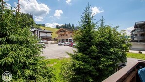 A hotel with a parking lot, a restaurant, and a view of the surrounding greenery and hills. - 200m from ski slopes, 1st floor, parking, tv, ski locker, 63m², Les Gets (Les Gets)