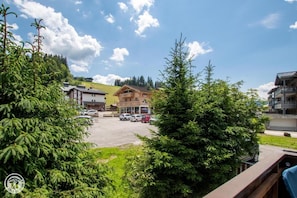 A hotel with a parking lot, a restaurant, and a view of the surrounding greenery and hills. - 100m from resort center, 1st floor, parking, tv, ski locker, 63m², Les Gets (Les Gets)