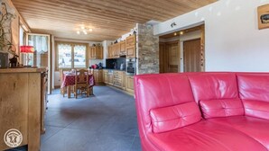 A cozy kitchen with wooden cabinets, a dining area with a table and chairs, and a red leather sofa in the living area. - 200m from ski slopes, 1st floor, parking, tv, ski locker, 63m², Les Gets (Les Gets)