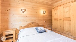 A wooden room with a bed, a nightstand, and a wardrobe. - 200m from ski slopes, 1st floor, parking, tv, ski locker, 63m², Les Gets (Les Gets)