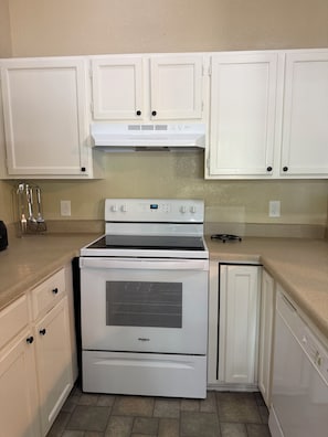 A kitchen with white cabinets, a Whirlpool stove, and a dishwasher.
