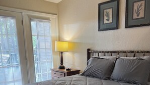 A bedroom with a bed, a nightstand with a lamp, and two framed pictures on the wall. - Charming 2-bedroom apartment with AC in Holly Lake Ranch (Holly Lake Ranch)