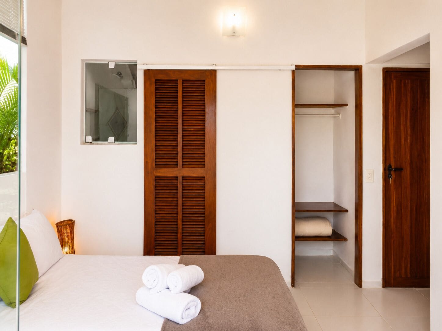 Un dormitorio con una cama, un armario de madera, un guardarropa y una ventana con persianas.