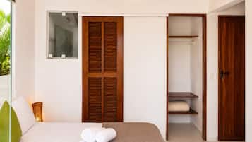 Un dormitorio con una cama, un armario de madera, un guardarropa y una ventana con persianas.