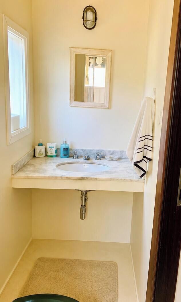 A bathroom with a sink, mirror, and toiletries.