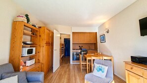 Ein kompakter Wohnbereich mit Küchenzeile, Essbereich und einer Sitzecke mit Sofa und Sesseln.