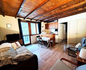A cozy room with a bed, a TV, a dining area with a table and chairs, and a kitchen area. - Ski-in/ski-out & foot of the slopes, 1st floor, balcony, tv, ski locker, 25m², Pra Loup (Pra Loup)