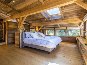 Ein geräumiges Schlafzimmer mit einem großen Bett, Holzbalken und Dachfenstern.