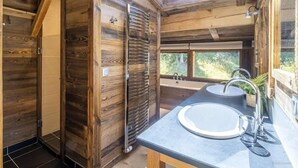 L’intérieur d’un chalet en bois, doté d’une lucarne, de deux éviers et offrant une vue sur l’extérieur.