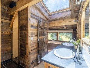 Ein Holzblock-Innenraum mit Oberlicht, zwei Waschbecken und Blick ins Freie.