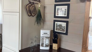 A kitchen with a white refrigerator, a coffee maker, a knife block, and framed pictures on the wall.