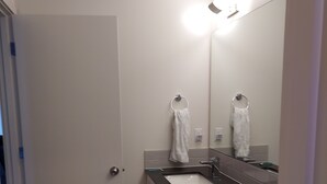 Een badkamer met een witte deur, een wastafel met spiegel en een vloer met een patroon.