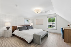 A bedroom with a bed, bedside tables, a lamp, a window, and a view of the outside.