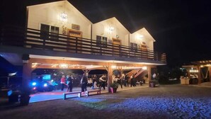 A two-story building with a balcony and a covered area with people gathered. - Villa Privada San Carlos (Ensenada)
