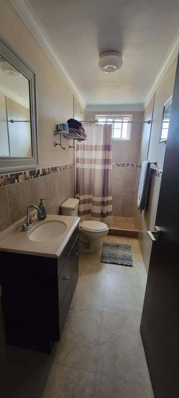 A compact bathroom with a sink, toilet, and shower area. - Villa Privada San Carlos (Ensenada)