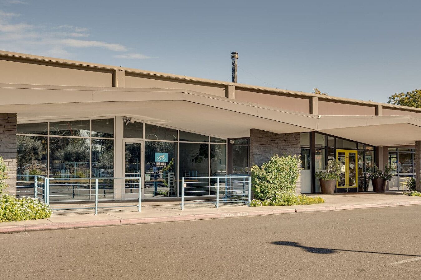 A building with a covered entrance, large windows, and a bike parking sign.