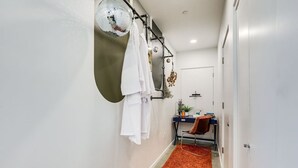Un pasillo con pared blanca, una bola de discoteca, toallas colgadas, un escritorio con planta y una alfombra roja.