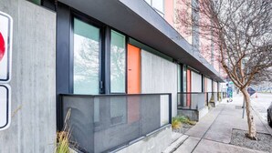 Un edificio moderno con amplios ventanales, fachada de hormigón y un árbol en primer plano.