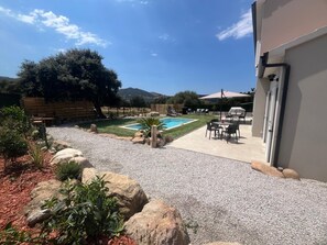 Un jardín con piscina, mobiliario de patio y vistas del paisaje circundante.