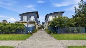 A residential street with two modern houses, a clear sky, and a well-maintained lawn. - Sirena by Experience Jervis Bay (Vincentia)