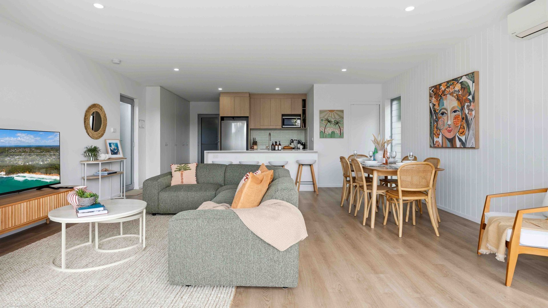 A modern living room with a sofa, dining table, and kitchen in the background.