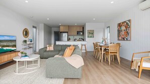 Una sala moderna con un sofá, una mesa de comedor y una cocina al fondo.