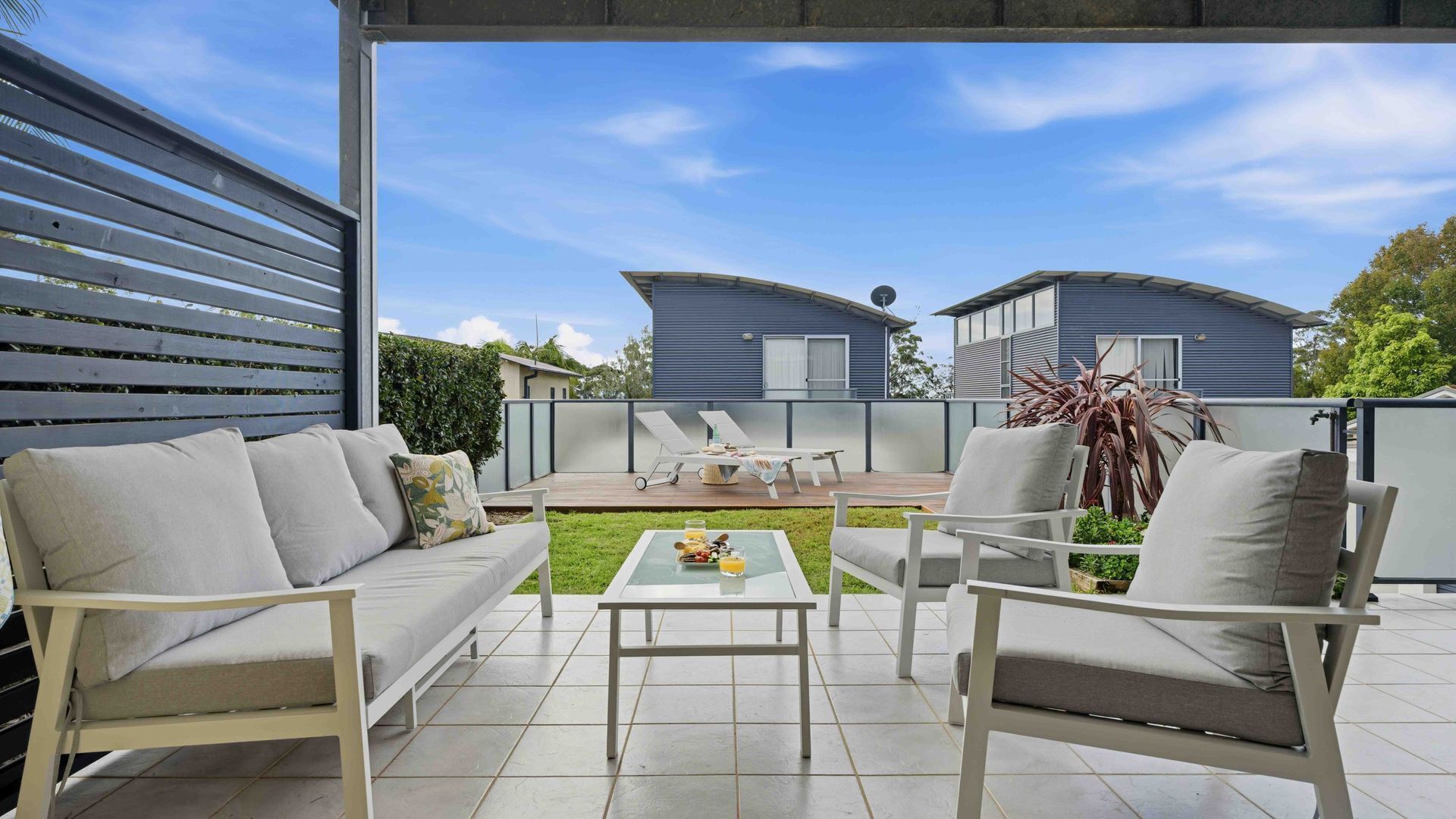Een terras buiten met een bank, stoelen en een tafel.