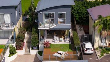 A two-story house with a balcony, a covered patio, and a car parked in the driveway.