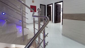 A modern interior with a metallic staircase, a hallway leading to a door, and a wall with a textured pattern. - hotel castiya (M'diq)