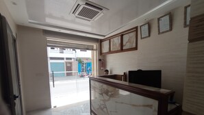 A hotel lobby with a marble floor, a reception desk, framed certificates on the wall, and a view of the street outside. - hotel castiya (M'diq)