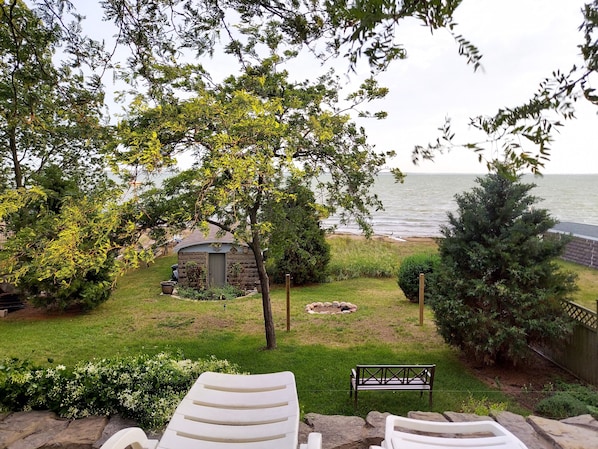 A garden with a stone structure, a bench, and a view of the sea.