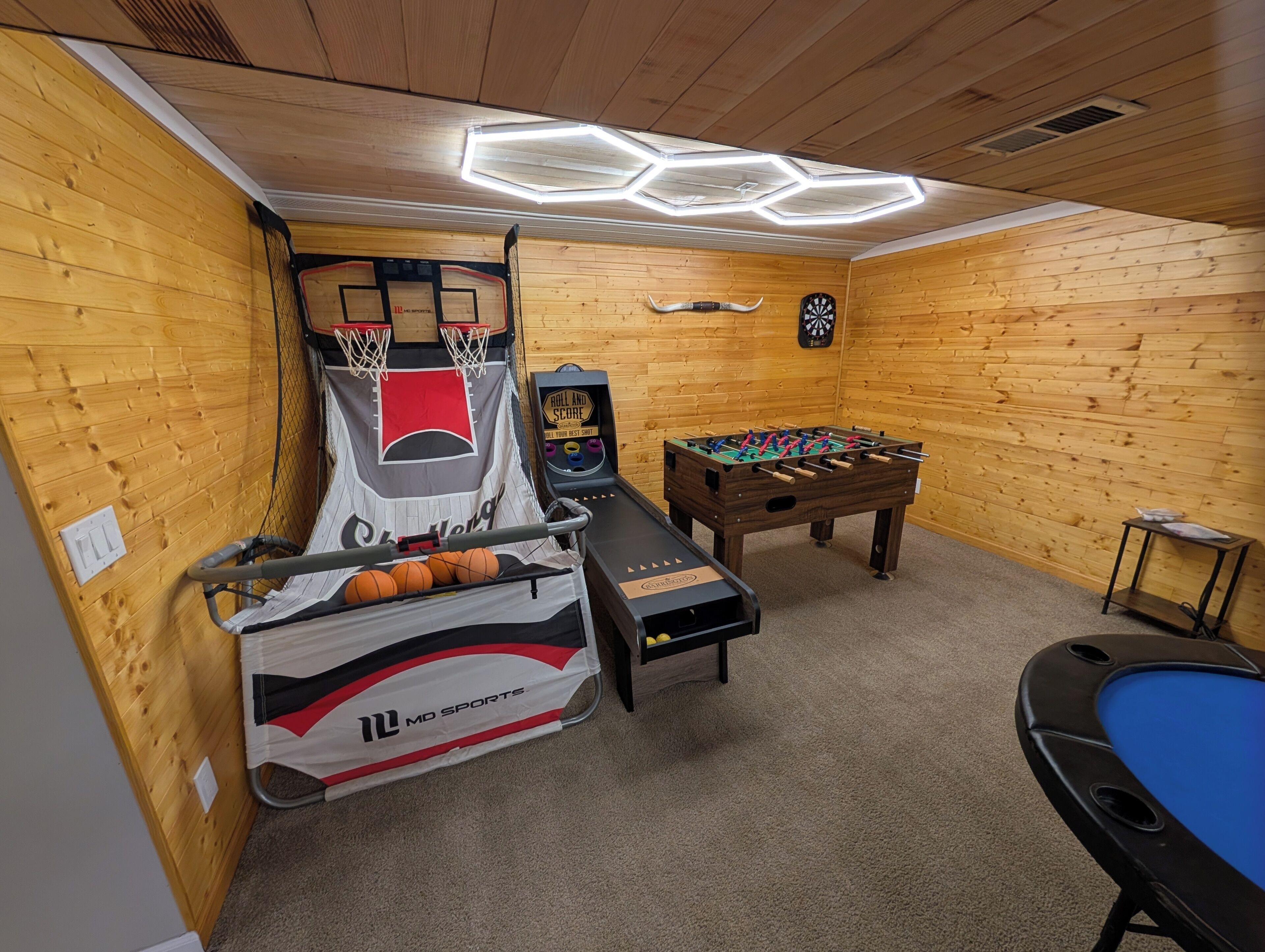 Um quarto com uma cesta de basquete, mesa de pebolim e mesa de bilhar.